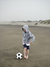 Boy kicking soccer ball on beach. Date : 2008