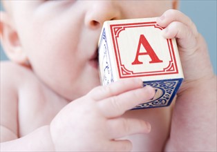 Close up of baby biting on alphabet block. Date: 2008