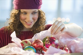 Woman unwrapping Christmas ornaments.