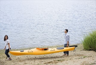 Couple carrying kayak. Date: 2008