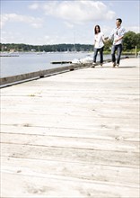 Couple holding hands and walking on dock. Date : 2008