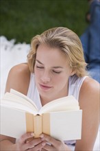 Woman reading book outdoors.