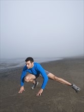 Man stretching on foggy beach. Date: 2008