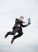 Businessman with laptop n mid-air. Date: 2008