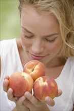 Woman smelling fresh peaches.