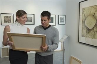 Curators examining painting in art gallery.