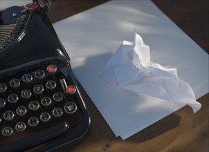 Crumpled paper next to antique typewriter.