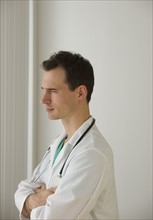 Male doctor looking out window pensively.