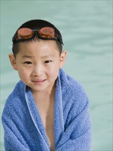 Boy wrapped in towel posing in front of swimming pool. Date: 2008