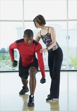 Fitness instructor helping man lunge with dumbbells. Date: 2008