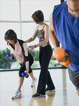 Fitness instructor helping woman lunge with dumbbells. Date: 2008