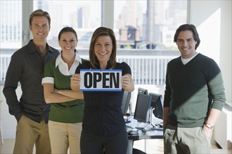 Portrait of business people holding ”Open” sign.