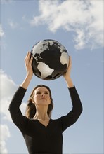 Woman holding globe overhead.