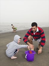 Family looking for shells on beach. Date: 2008