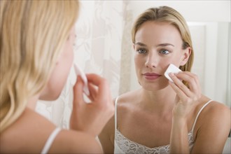 Woman applying makeup in bathroom.