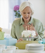 Senior woman looking at birthday cake.