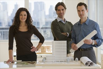 Portrait of architects with building model and blueprints.