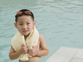 Boy wrapped in towel posing in front of swimming pool. Date: 2008
