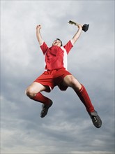 Soccer player jumping in mid-air with trophy. Date : 2008