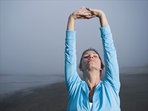 Woman stretching on foggy beach. Date: 2008