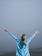 Woman with arms outstretched on foggy beach. Date : 2008