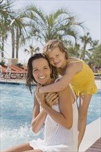 Portrait of mother and daughter hugging at poolside. Date : 2008