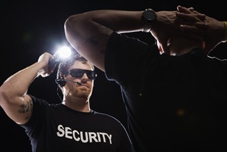 Security guard shining flashlight on man. Date : 2008