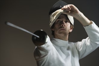 Man pointing fencing foil and lifting mask. Date: 2008