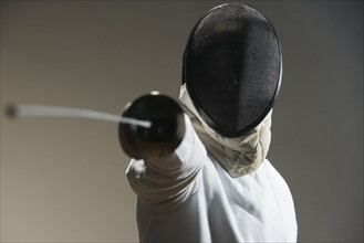 Close up of fencer in mask pointing fencing foil