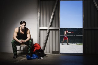 Man sitting on stool by doorway with boxer in background. Date : 2008