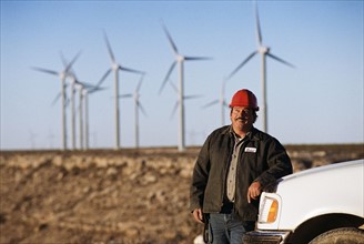 Worker leaning against truck with wind turbines in background. Date : 2008