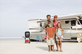 Family posing on beach in front of motor home. Date: 2008