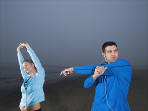 Couple stretching on beach. Date: 2008