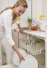 Woman loading plates in dishwasher.