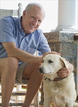 Portrait of senior man sitting on porch with dog.