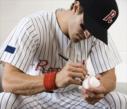 Close up of baseball player autographing baseball. Date: 2008
