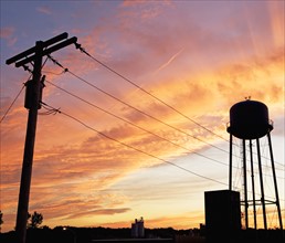 Water tower and telephone pole against sunset sky. Date: 2008
