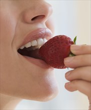 Close up of woman biting strawberry.