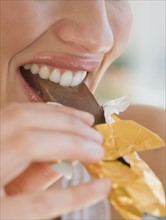 Close up of woman biting chocolate bar.