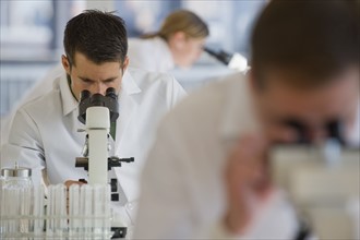 Scientists using microscopes in pharmaceutical laboratory.