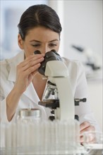 Scientist using microscope in pharmaceutical laboratory.