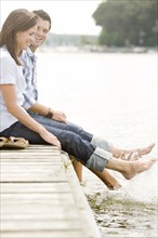 Couple sitting on dock and splashing feet in lake. Date: 2008