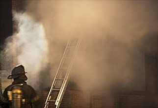 Firefighter standing outside burning building. Date : 2008