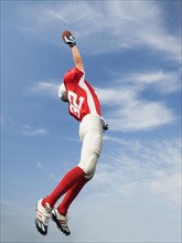 Football player in mid-air reaching for football. Date: 2008