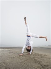 Portrait of girl doing handstand on beach. Date : 2008