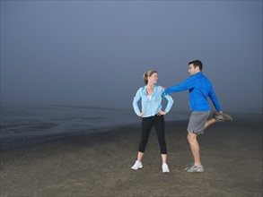 Couple stretching on beach. Date: 2008