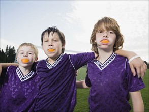 Portrait of boys in soccer uniforms with orange wedges in mouth. Date : 2008