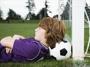 Boy laying on soccer ball against goal. Date : 2008