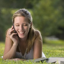 College student reading in grass and talking on cell phone. Date: 2008