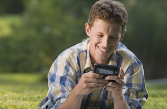 Man laying in grass and text messaging. Date : 2008